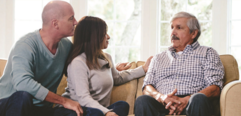 Three people sitting on a couch having a conversation